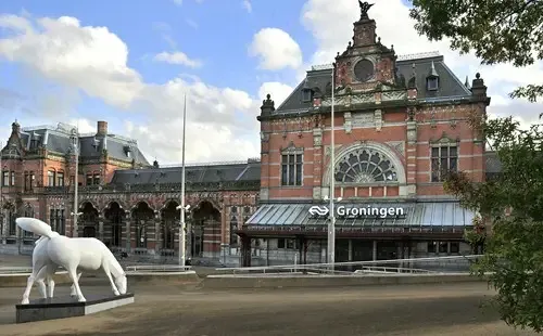 Hoofdgebouw van station Groningen met het witte paardenbeeld op het stationsplein
